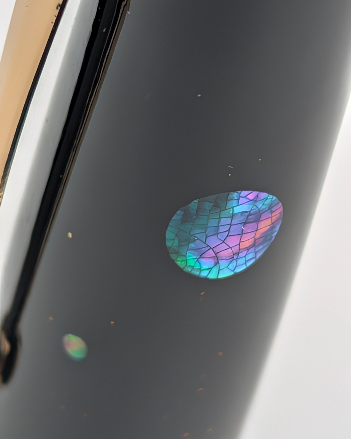 Macro of a mother-of-pearl inlay with a fine crackle pattern on the Liberum Star Shine cap